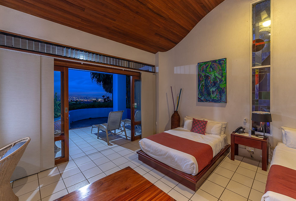 hotel room with white and red bed, tiles, pictures and wooden ceiling
